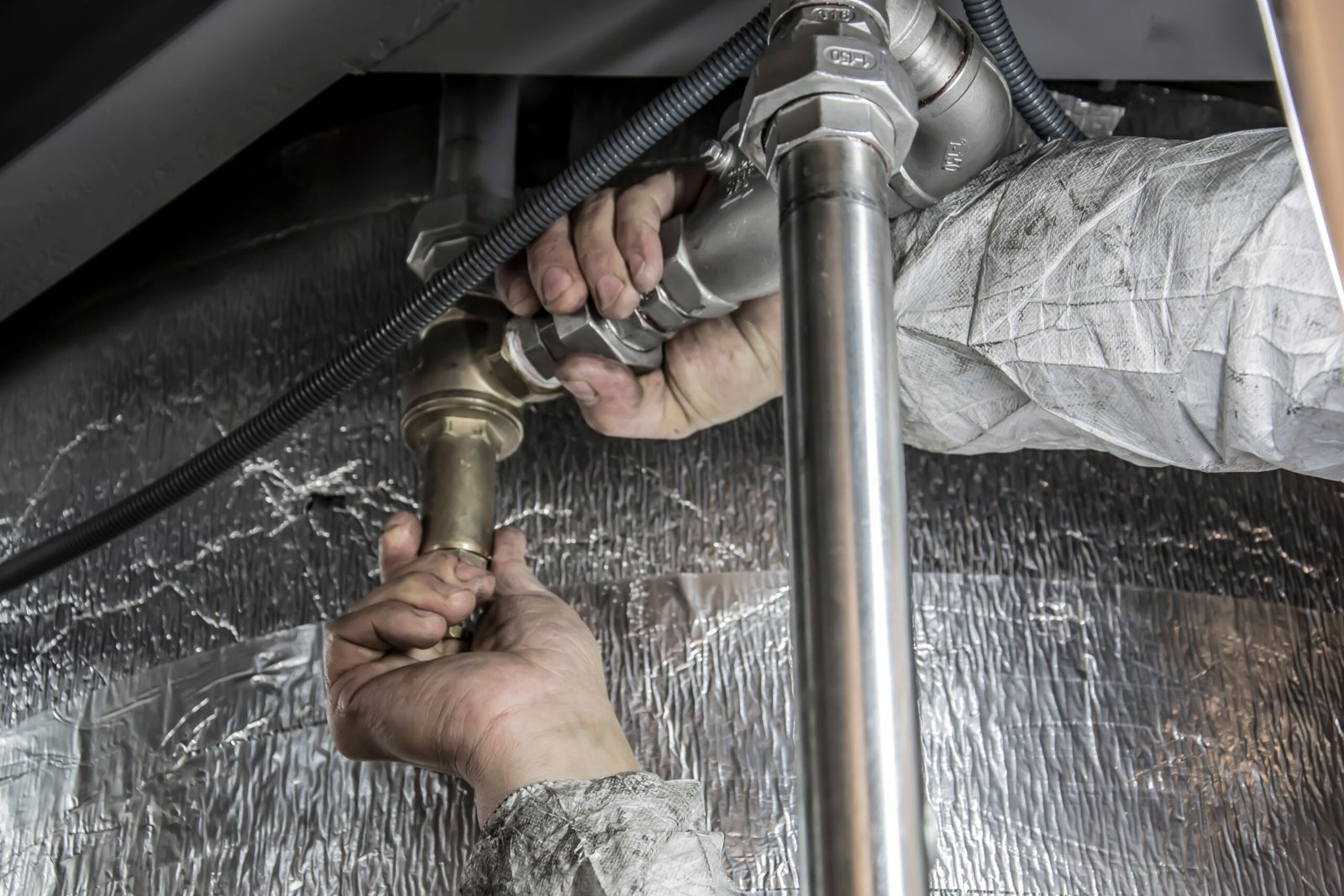 Plumber working on pipework under a sink